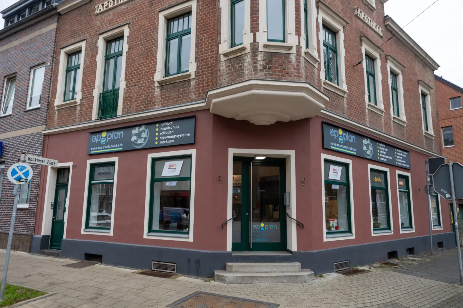 Eckhaus mit Eckeingang und Werbung von Ep-plan und den Marken.